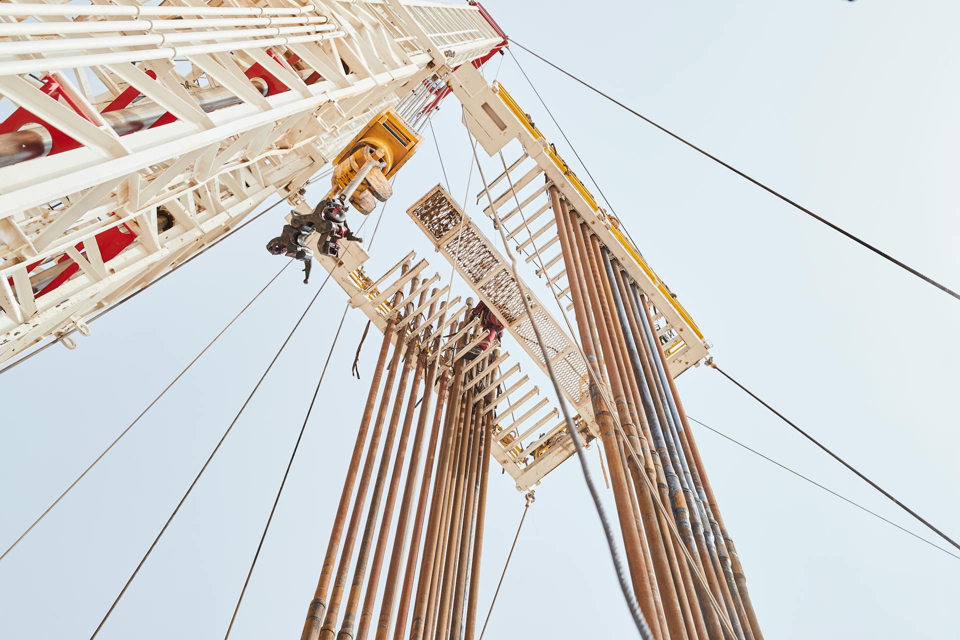 View looking up at towering construction cranes and steel beams at a building site.